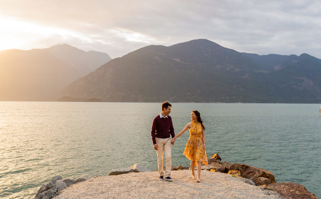 couple walking along Porteau Cove during sunset for their engagement session