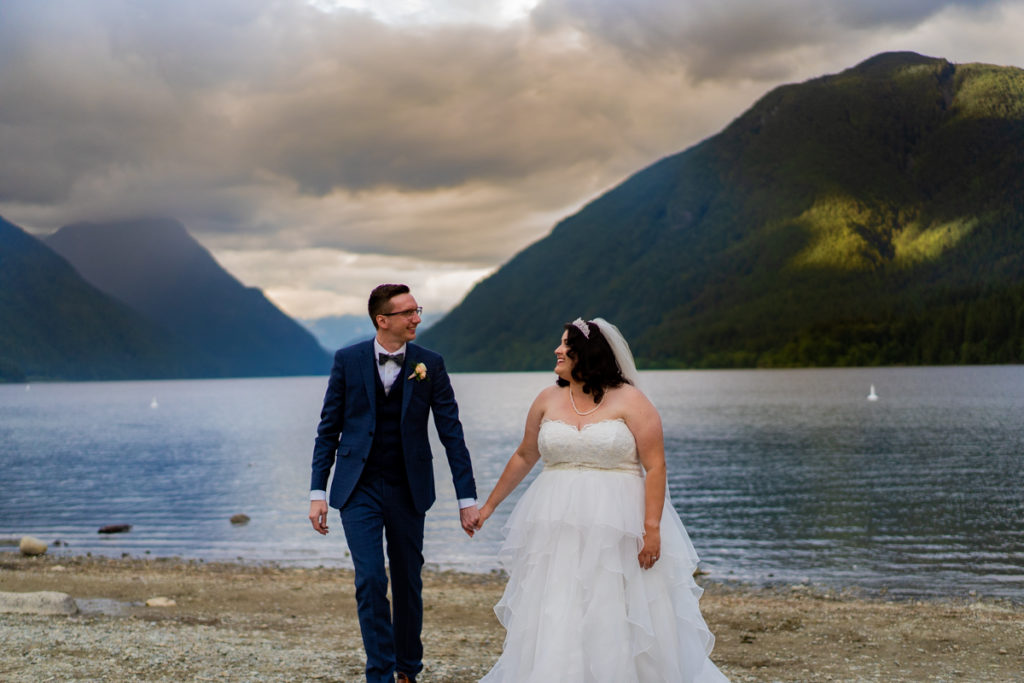 bride and groom walking on the beach at Alouette lake in Golden Ears Provincial Park