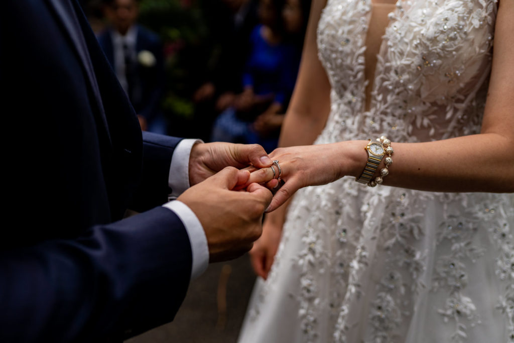 groom placing a wedding ring onto the brides hand 