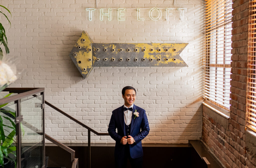 Groom standing below the Loft sign at The Loft at Earls Yaletown