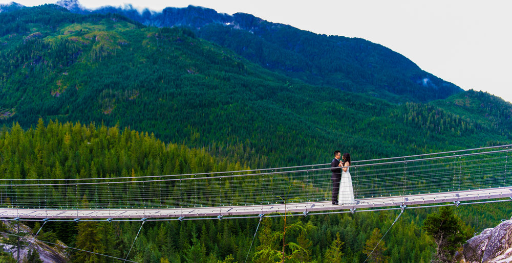 Sea to Sky couple on the bridge with mountains in the back