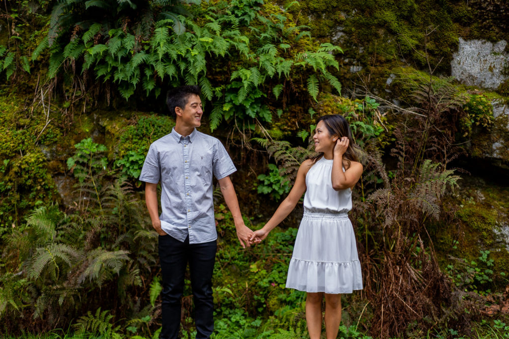 Couple in front of a grass wall for their Othello Tunnels engagement photos