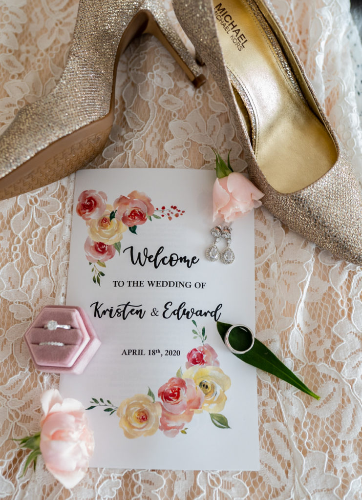 Wedding invitation, ring, and shoes on wedding dress